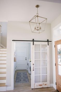 an open door leading to a hallway with a chandelier hanging from the ceiling