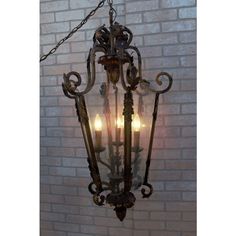 an old fashioned chandelier hanging from a brick wall with three candles in it