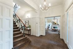 a staircase leading up to the second floor in a large white house with chandelier