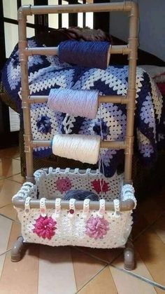 a crocheted basket with yarn on it and two rolls of thread hanging from the top