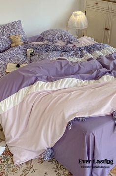 an unmade bed in a bedroom with purple sheets and pillows on top of it