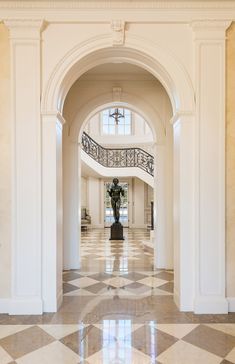 an archway leading to the second floor of a house with marble floors and white walls