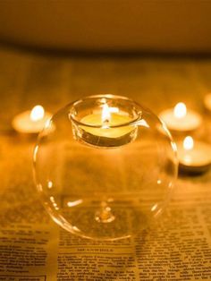 several lit candles in a bowl on top of a newspaper