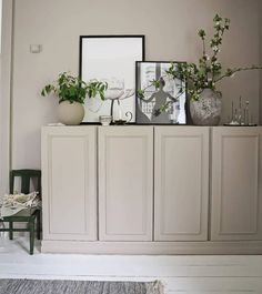 a white cabinet with plants and pictures on top