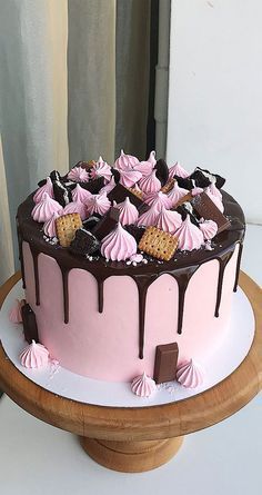 a pink and chocolate cake on a wooden stand