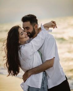 a man and woman hugging on the beach