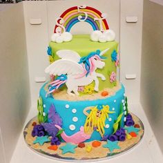 there is a cake decorated with an unicorn on the top and rainbows in the bottom