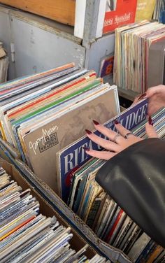 a woman's hand reaching for records in a record box filled with vinyls