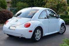 a white volkswagen beetle parked in a driveway