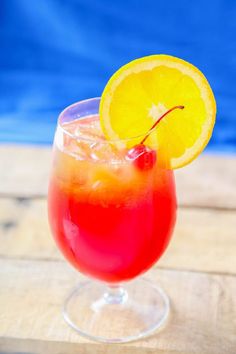 a red drink with an orange slice on the rim