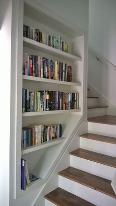 there are many books on the shelves next to the stairs