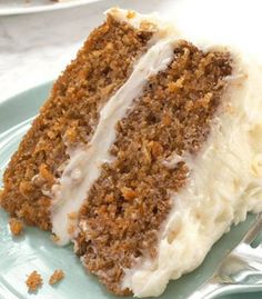 a slice of carrot cake on a blue plate with a silver fork and white frosting