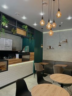 the interior of a restaurant with tables, chairs and lights hanging from the ceiling above