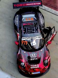 a red and black car parked on top of a parking lot