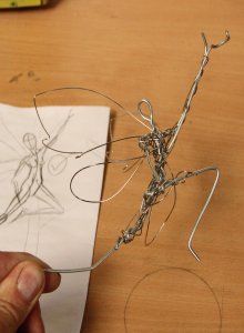 a person is working with wire art on a piece of paper that looks like an insect