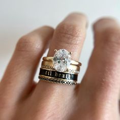 a woman's hand holding a ring with a diamond in the center and two bands around it