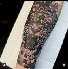 a man's arm with a tiger tattoo on it and flowers in the background