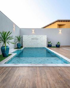 an empty swimming pool in the middle of a backyard with grass and potted plants