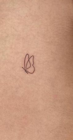 a small butterfly tattoo on the back of a woman's left arm and stomach