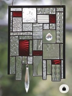 a stained glass sun catcher hanging from a window with raindrops on the windowsill