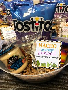 a bowl filled with food and snacks sitting on top of a table next to bags of chips