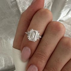 a woman's hand holding an engagement ring with a large diamond in the center