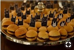 small hamburgers with finger prints on them are displayed on a platter at a party