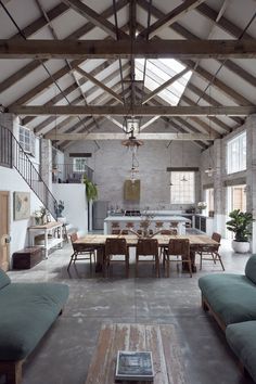 a large open living room and dining area with exposed ceilings, wood beams and stone walls