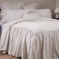 a bed with white and grey striped sheets