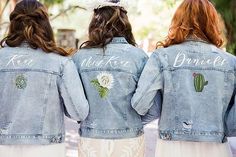 three women wearing denim jackets with embroidered words on the back and cactus designs on them