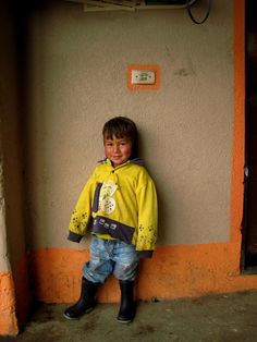 a little boy that is standing up against a wall