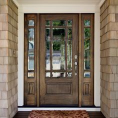 the front door to a house with two windows and a rug on the floor in front