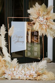 an arrangement of flowers and feathers on display in front of a building with signage for the wedding venue