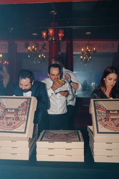 three men and two women standing in front of boxes with designs on them, one man is holding a piece of food