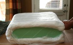 a person is wrapping up a mattress on a table in front of a door and window