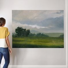 a woman standing in front of a painting on the wall with her back to the camera