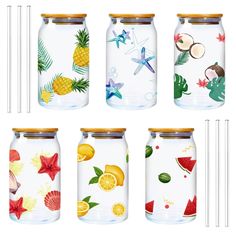 four glass jars with different designs and straws in them, all decorated with tropical fruit