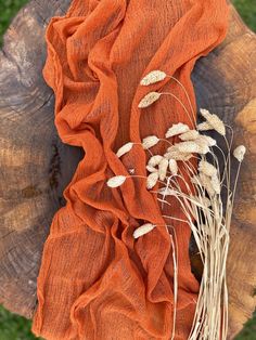 an orange scarf on top of a piece of wood with grass growing out of it