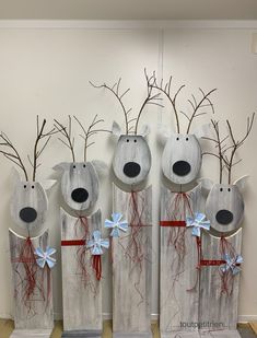 four wooden reindeers with blue bows and branches in their mouths are standing next to each other