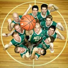 a group of young men standing next to each other on top of a basketball court