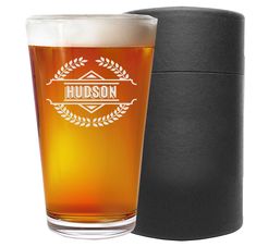 a beer glass sitting in front of a black box with the word hudson on it