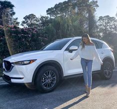 a woman standing next to a white mazda cx - 5