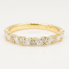 a yellow gold wedding band with five pear shaped diamonds on the top and bottom half