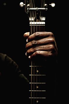 a close up of a person holding an acoustic guitar with their hands on the strings