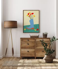 a painting on the wall above a dresser with flowers in a blue boot sitting on it