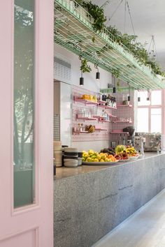 an open kitchen with lots of food on the counter and hanging plants in the ceiling