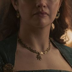 a close up of a woman wearing a necklace and earrings on her neck, looking off to the side