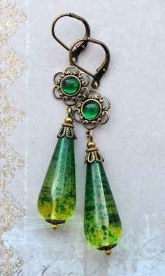 VINTAGE ELEMENTS Unique Jewellery, Handmade from Vintage Inspired Original Designs Exquisite, Art Nouveau, Art Deco style antiqued Brass Earrings with long Emerald and Olivine Green Fusion Lucite Drops, and Filigree Flower detail with set glass cabochons. These earrings have antiqued brass leverback earwires and measure 6.7cm from the top of the earwires. Handmade Vintage Long Drop Jewelry, Vintage Green Jewelry With Intricate Design, Vintage Green Brass Earrings, Antique Finish Vintage Earrings, Ornate Green Earrings With Intricate Design, Vintage Green Decorative Jewelry, Vintage Green Dangle Jewelry, Victorian Handmade Green Earrings, Vintage Teardrop Jewelry With Intricate Design