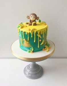 a birthday cake with a monkey sitting on top of it and dripping yellow icing