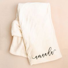 a white blanket with the word ananda written on it next to an alarm clock